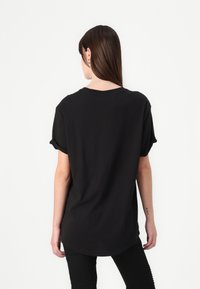 Black short-sleeve t-shirt with a round neckline and a relaxed fit. Fabric is smooth with a slightly longer back hem.