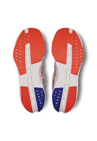 Baskets de course avec une semelle extérieure texturée rouge, bleue et blanche. Les caractéristiques comprennent des trous de ventilation et un design rembourré et flexible.