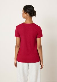 Raudona trumpa rankovėmis marškinėliai su apvaliu iškirpimu, pagaminti iš minkštos medžiagos. Turi tiesų kirpimą ir šiek tiek išlenktą apatinę dalį patogumui.