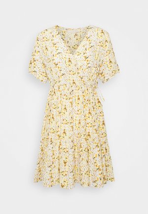 Valkoinen kietaisumekko, jossa keltainen kukkakuosi. Lyhyet hihat, V-kaula-aukko ja vyötäröllä poimutettu kohta. Leveä helma, jossa kerroksittainen muotoilu.