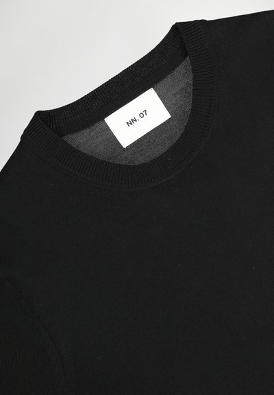 Schwarzes Baumwoll-T-Shirt mit Rundhalsausschnitt, das ein einfaches Etikett mit der Aufschrift "NN. 07" am Halsausschnitt trägt. Glatte Textur, minimalistisches Design.