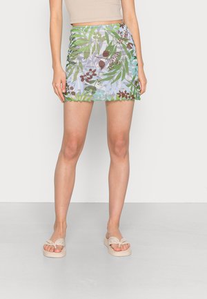 Saia mini colorida com um padrão floral tropical em tons de verde e castanho, com uma bainha com recortes e uma textura de tecido suave.