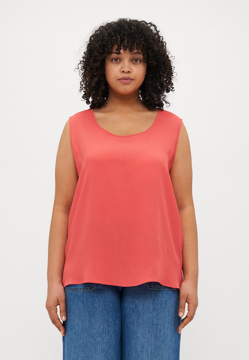 Coral sleeveless top with a rounded neckline, made of smooth fabric. Paired with blue wide-leg jeans. Simple, clean design with no patterns.
