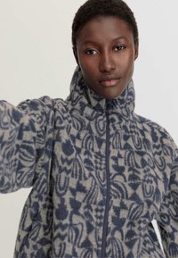 Fleece jack met een hoge kraag, ritsluiting en een ingewikkeld blauw-grijs patroon. Zachte textuur met een ontspannen pasvorm.