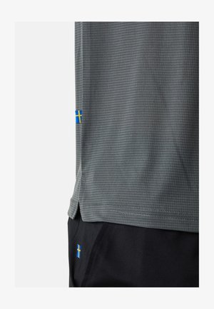 Grå atletisk skjorte med et tekstureret mønster, der har blå og gule svenske flag på nederste kant og siden. Korte ærmer og buet bund.