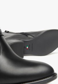 Stivaletti neri in pelle con chiusura a cerniera, texture liscia, tacco basso e suola testurizzata. Taglia 37, made in Italy.