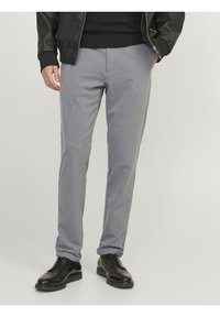 Gray tailored trousers with a smooth texture, fitted cut, and subtle waistband. Paired with black leather shoes.