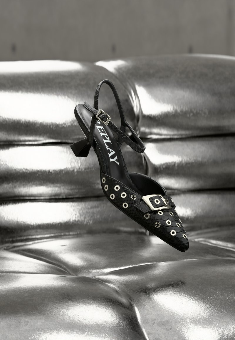 Μαύρο παπούτσι slingback με μυτερή μύτη, με ασημί κοχλίες και διακοσμητικό πόρπη. Κατασκευασμένο από υλικό με υφή και μικρό τακούνι μπλοκ.