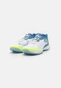Scarpe sportive con una tomaia blu, pannelli in rete bianchi, dettagli giallo neon e una suola traslucida con un motivo di presa testurizzato.