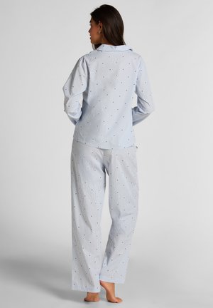 Lichtblauw pyjamaset met witte strepen en kleine zwarte stippen. Het shirt heeft een kraag en de broek heeft een losse pasvorm.