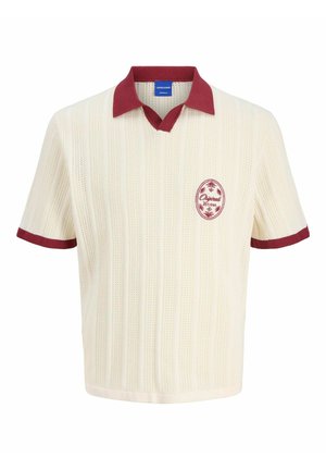 Polo shirt crème à manches courtes avec un design tricoté texturé, col et finitions bordeaux, arborant un logo circulaire rouge sur la poitrine.