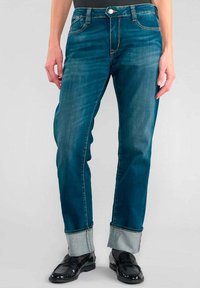 Jean en denim bleu à coupe droite, avec un bouton de fermeture, un léger délavage et des poignets retroussés mettant en valeur une doublure intérieure plus claire.