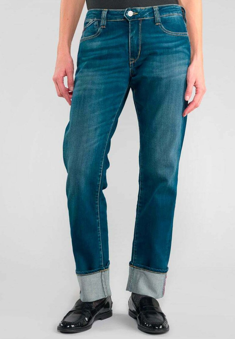 Jean en denim bleu à coupe droite, avec un bouton de fermeture, un léger délavage et des poignets retroussés mettant en valeur une doublure intérieure plus claire.