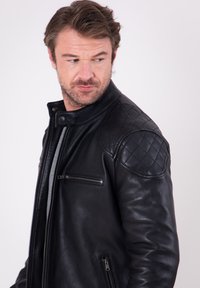 Black leather jacket featuring a quilted shoulder design, front zippers, and a snap collar detail. Smooth texture with a fitted silhouette.