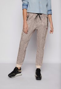 Pajamabyxor i beige och svart djurmönster. Har resårmidja, dragsko, sidofickor och avsmalnande muddar. Materialet verkar mjukt.