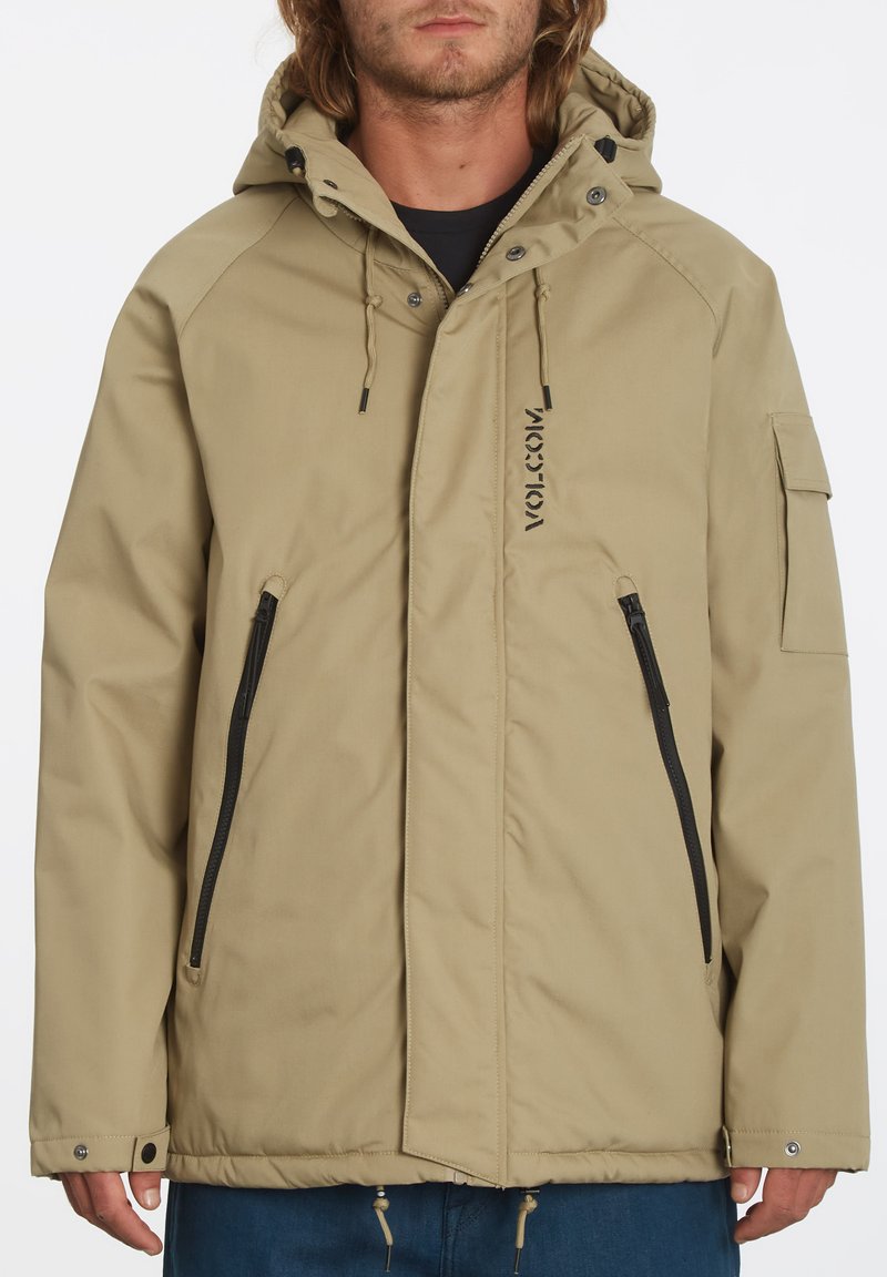 Beige hoodie met een rits aan de voorkant, twee ritszakken en een logo. Bevat verstelbare trekkoorden en een gestructureerde stof.