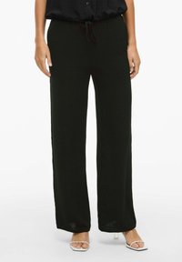 Fekete, laza szabású nadrág, puha, textúrált anyagból készült. Rugalmas derékpántja van, húzózsinórral és széles szárakkal.