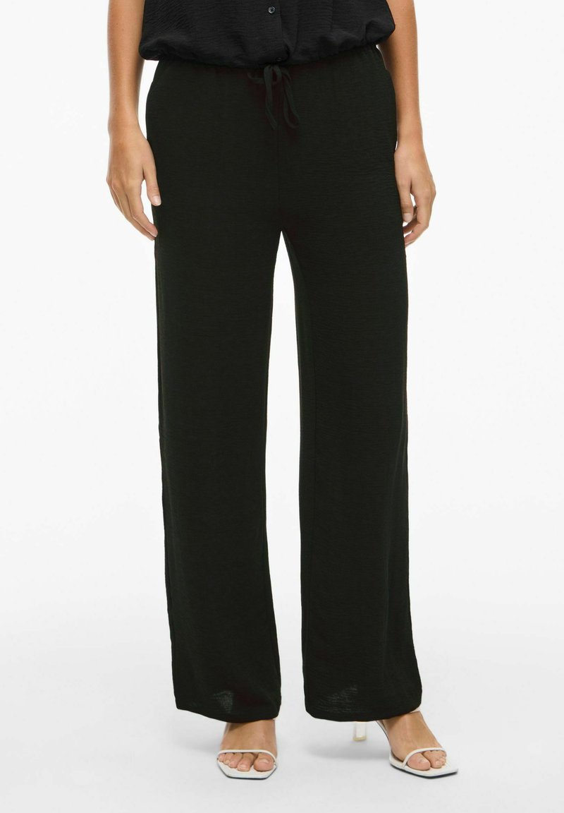 Fekete, laza szabású nadrág, puha, textúrált anyagból készült. Rugalmas derékpántja van, húzózsinórral és széles szárakkal.