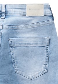 Ljusblå denimjeans med en enda bakficka med sömnadsdetaljer och en rektangulär etikett vid midjan som säger "Street One."