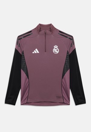 Lilla pikkade varrukatega sportlik särk kvartstõmblukuga, mustade detailide, valge Adidas logo ja Real Madridi embleemiga. Tekstureeritud küljesektsioonid.