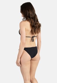 Ensemble de bikini noir avec un haut à nouer dans le dos et un bas taille haute. Tissu lisse, design minimal et couleur unie classique.
