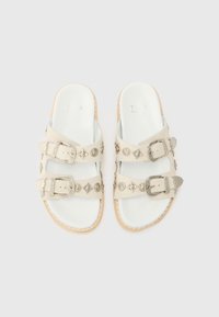 Sandali bianchi slip-on con due fasce larghe, hardware con fibbia argentata e decorazioni. Soletta sagomata con suola leggera.