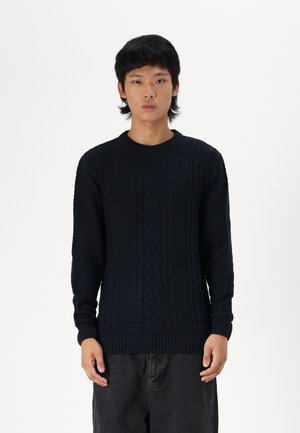 Suéter de punto azul marino con patrones de cable texturizados, cuello redondo y puños y dobladillo acanalados. Diseño de ajuste regular con mangas largas.