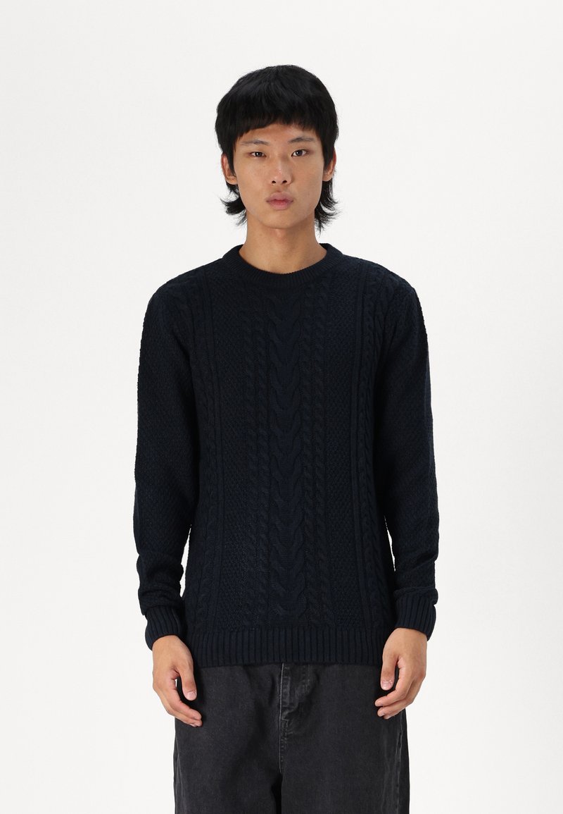 Suéter de punto azul marino con patrones de cable texturizados, cuello redondo y puños y dobladillo acanalados. Diseño de ajuste regular con mangas largas.