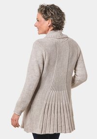 Strickjacke in hellem Beige mit geripptem Kragen, strukturiertem Rücken und gefälteltem Detail nahe dem Saum. Weicher, gemütlicher Stoff.