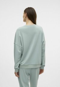 Lys grøn sweatshirt lavet af blødt stof. Har dropped skuldre, en afslappet pasform og ribbede manchetter ved håndleddene og livet.