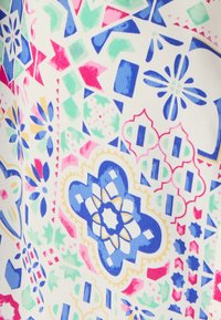 Tessuto multicolore con intricati motivi geometrici e floreali. I colori principali sono blu, rosa, verde e giallo su uno sfondo bianco.