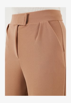 Beige maßgeschneiderte Hosen aus strukturiertem Stoff, mit Falten vorne und einem breiten Bund, der einen rechteckigen Gürtelschlaufenakzent aufweist.