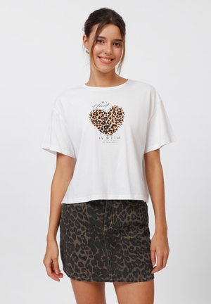 White cropped t-shirt with "MY HEART IS WILD" text and leopard heart graphic, paired with a black leopard print denim skirt.