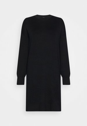 Robe pull noire à manches longues, col rond, avec poignets et ourlet côtelés sur fond blanc uni.