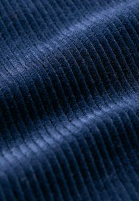 Temno modra kordura tkanina z drobnimi, vertikalnimi rebri in mehko teksturo, ki poudarja izmenične vzorce svetlobe in sence.