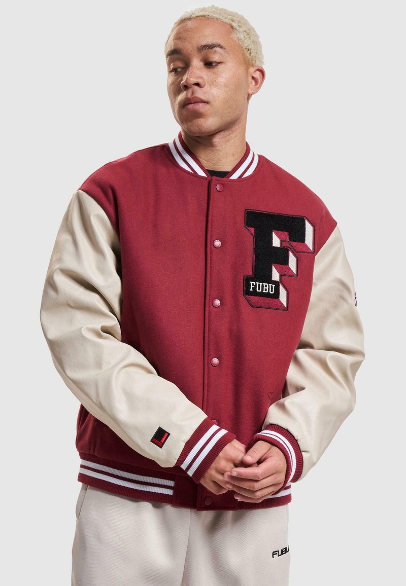 Veste universitaire rouge et crème avec col en tricot, logo "F" brodé, boutons-pression et poignets côtelés rayés. Tissu doux avec des manches contrastantes.