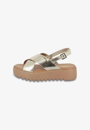 Goldene metallische Sandalen mit überkreuzten Riemen und einer verstellbaren Knöchelchnalle. Flache Plattformsohle mit einer strukturierten, geriffelten Kante.