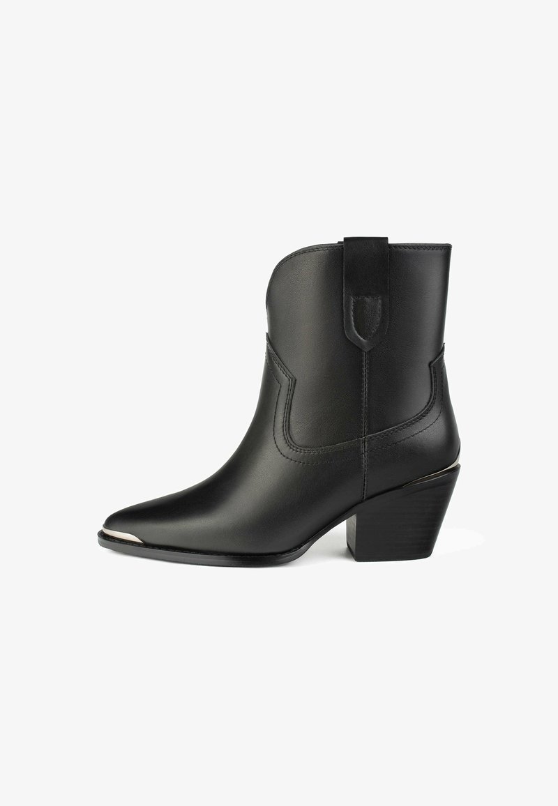 Botte en cuir noir à bout pointu, avec des coutures décoratives, une languette de traction et un heel bloc de hauteur intermédiaire. Accentuée par un capuchon métallique.