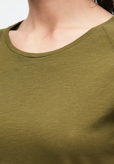 Λαδί πράσινο T-shirt με στρογγυλή λαιμόκοψη, κοντά μανίκια και απαλό, ελαφρύ ύφασμα. Διαθέτει ελάχιστες ραφές και καθημερινό σχεδιασμό.