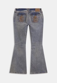 Μπλε τζιν από denim με καμπάνα στα πόδια, δύο πίσω τσέπες με καπάκια και κουμπιά και κεντημένο καφέ λογότυπο σε κάθε τσέπη.