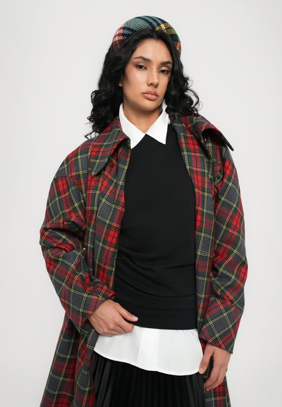 Cappotto a quadri in rosso, grigio e giallo con colletto strutturato; indossato sopra un top nero e una camicia bianca; abbinato a un cerchietto a scacchi.