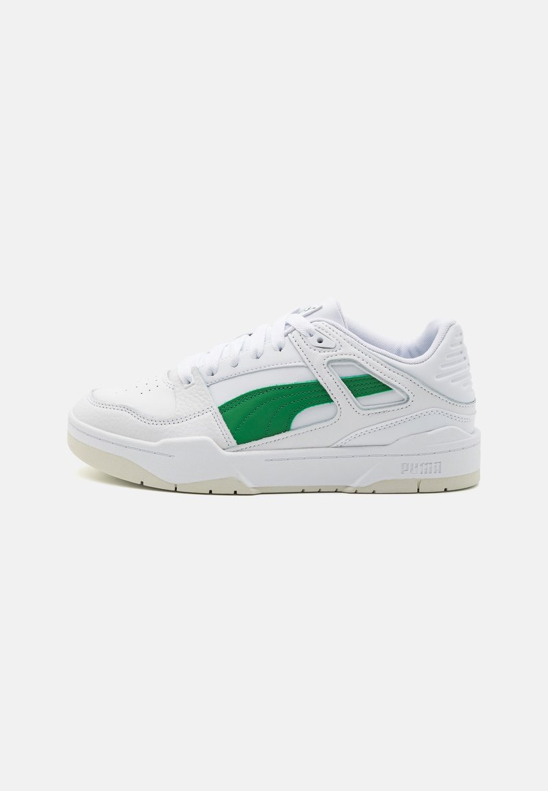 Hvit atletisk sneaker med grønne aksenter og teksturerte overlegg. Inkluderer en polstret krage og en gummisåle med en logo på hælen.