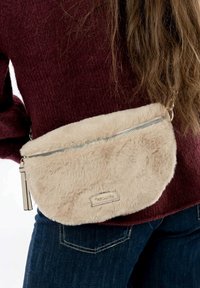 Sac à main en fausse fourrure beige avec fermeture éclair, dotée d'une fermeture éclair en argent lisse et d'une petite étiquette de logo. Forme ovale compacte, porté en bandoulière.