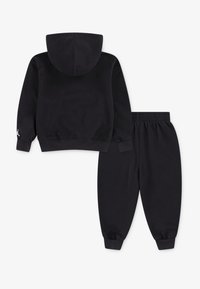 Black hoodie and pants set made from soft cotton. Hoodie features a kangaroo pocket and a hood; pants have an elastic waistband and cuffs.