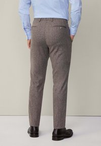 Szare wełniane spodnie o teksturowanym wykończeniu, slim fit, z dwiema tylnymi kieszeniami. W połączeniu z czarnymi skórzanymi butami i jasnoniebieską koszulą.
