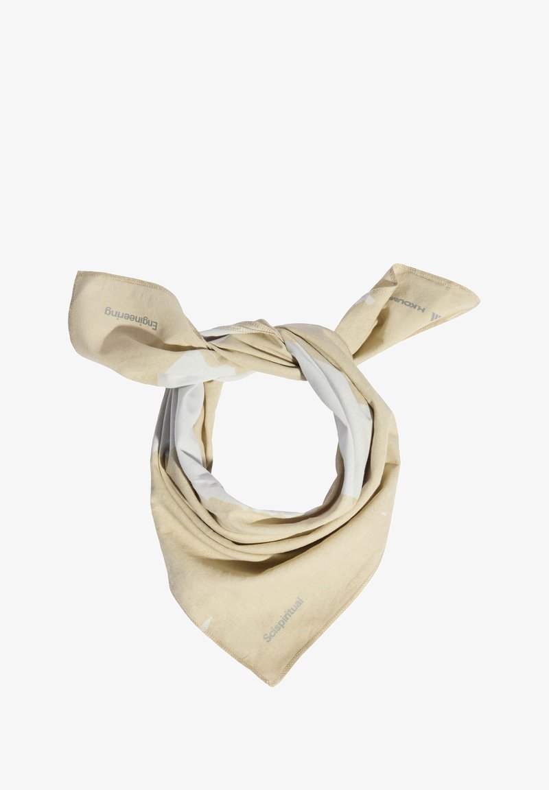 Bufanda beige y blanca con un patrón, fabricada con tela suave, mostrada en forma de lazo con extremos puntiagudos. Presenta una marca sutil a lo largo del borde.