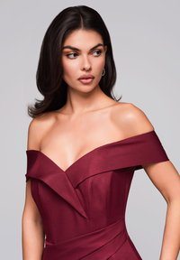 Burgundská off-shoulder šaty s vrstveným volánkovým detailem, přiléhavým korzetem a hladkou texturou, s elegantní siluetou a výrazným pasem.