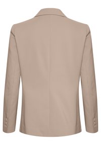 Beige kavaj med en slät yta, enkel bakslits, notched krage och långa ärmar med fyra knappdetaljer vid varje manschett.