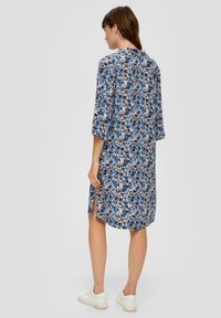 Blumenhemdkleid in Blau, Schwarz und Pink mit Dreiviertelärmeln, seitlichen Schlitzen und lockerer Passform, aus einem leichten Stoff gefertigt.