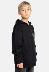 Černá zipová mikina s kapsou vpředu, žebrovanými manžetami a barevným kruhovým logem na hrudi. Měkká tkanina a mírně oversize střih.